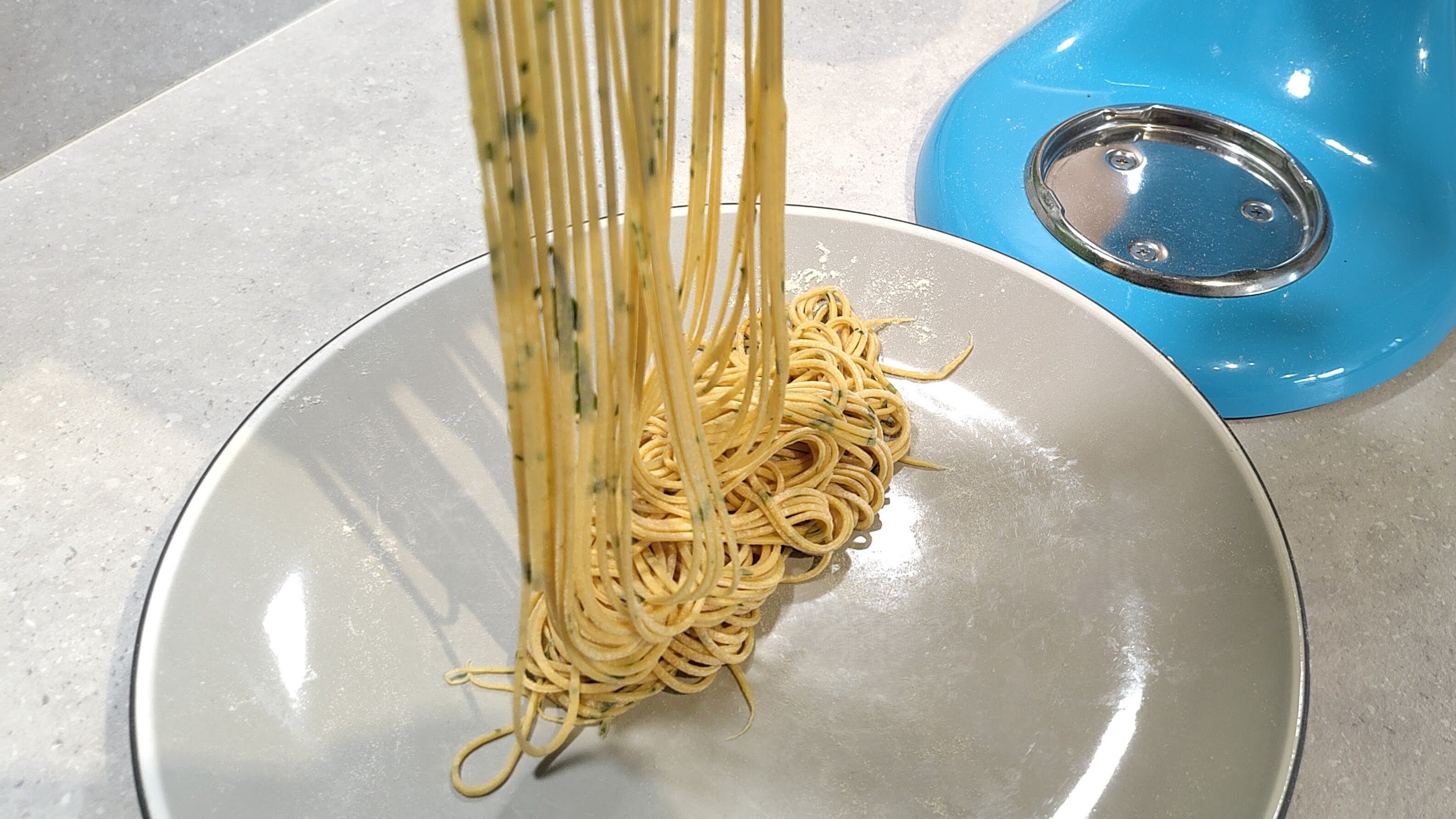 KitchenAid stand mixer with pasta roller attachment cutting tomato and basil spaghetti