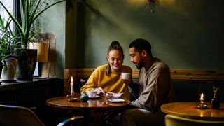 Woman and man sitting in a cafe sharing coffee and cake, talking