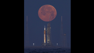 The pink moon sets behind NASA's Artemis 1 Space Launch System rocket on Saturday, April 16, 2022.