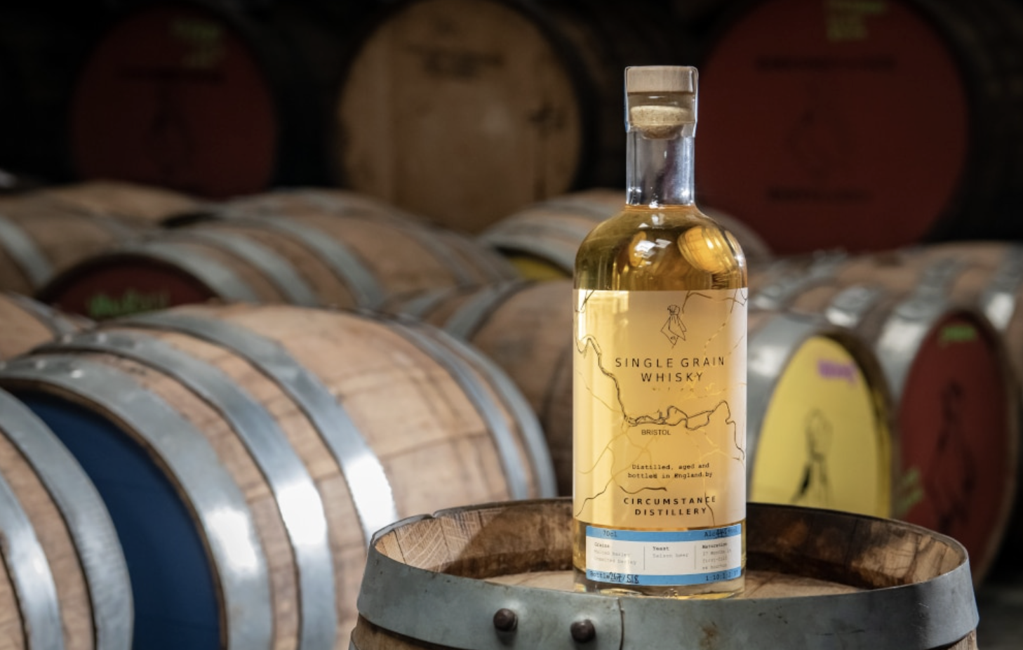an image of a bottle of Single Grain whisky from Circumstance Distillery in Bristol, sitting on a wooden barrel