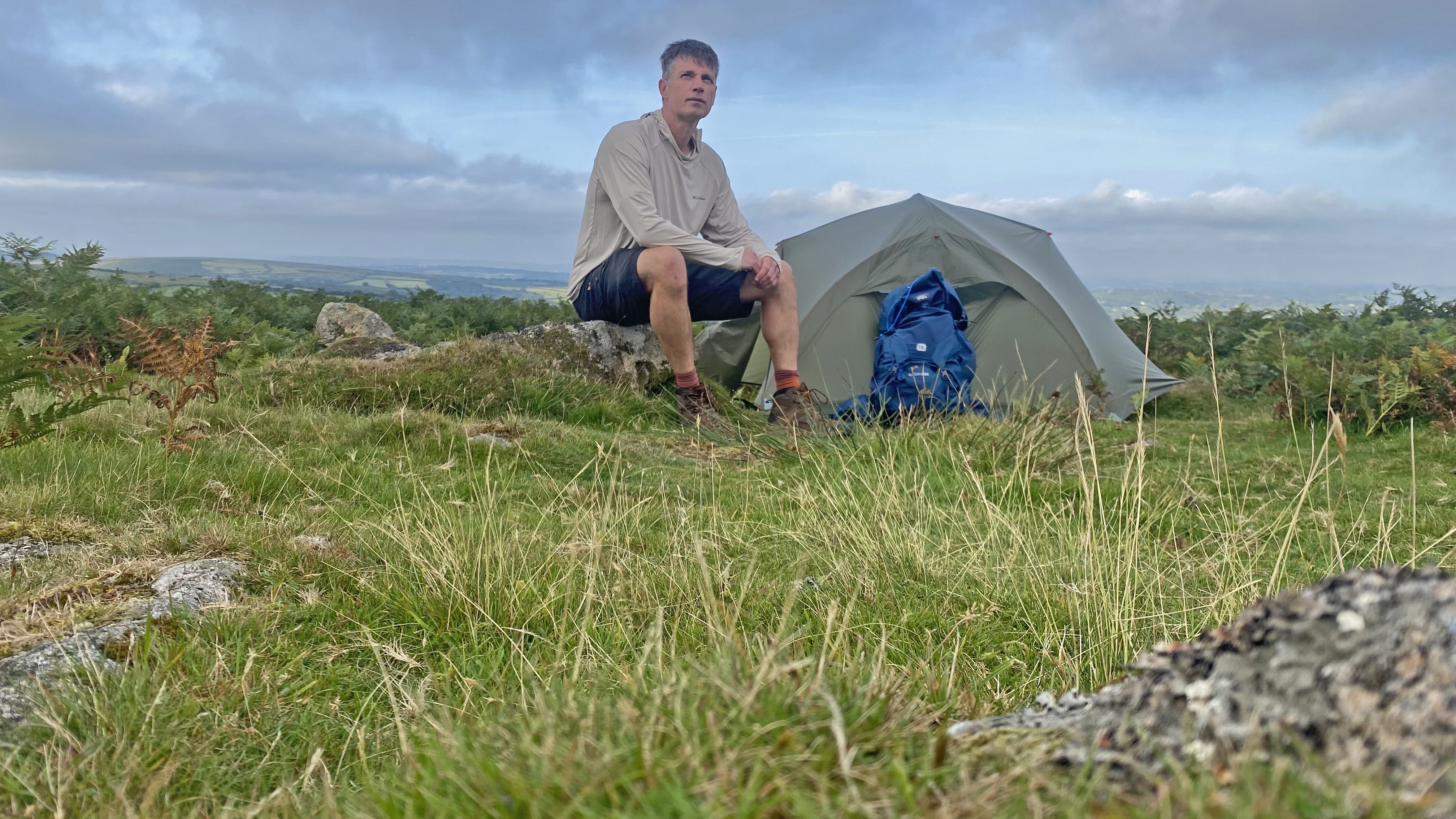 Camper wearing the Columbia Skien Valley Hoodie, beside a tent