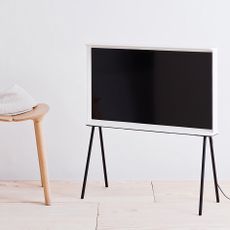 Samsung Serif TV on a stand next to a wooden stool