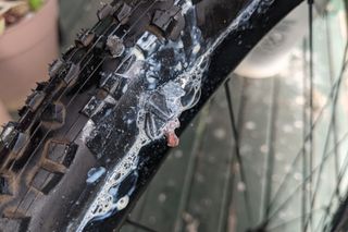 Tubeless plug and sealant working in tandem to seal a large hole in a bicycle tyre