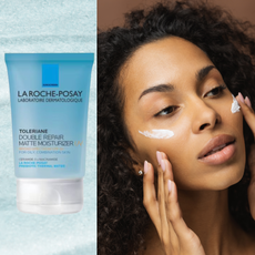 A woman with two swipes of SPF on her cheeks next to a bottle of sunscreen.