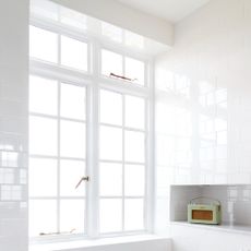A white-tiled bathroom with a large window