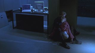 Kiefer Sutherland holds Leslie Hope on the floor in a dark office in 24.