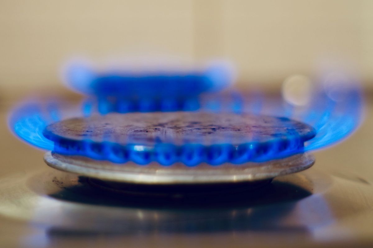 A gas stove with two hobs lit with blue flames