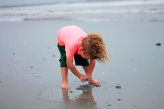 This boy won’t remember all the shells he digs up, but he’ll learn that the beach is the place to find them.