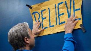 Nate putting up the newly taped together Believe sign.