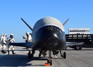Specially garbed technicians attend to an X-37B spacecraft after it landed at NASA's Kennedy Space Center in Florida, ending the fourth Orbital Test Vehicle (OTV-4) mission in May of last year.