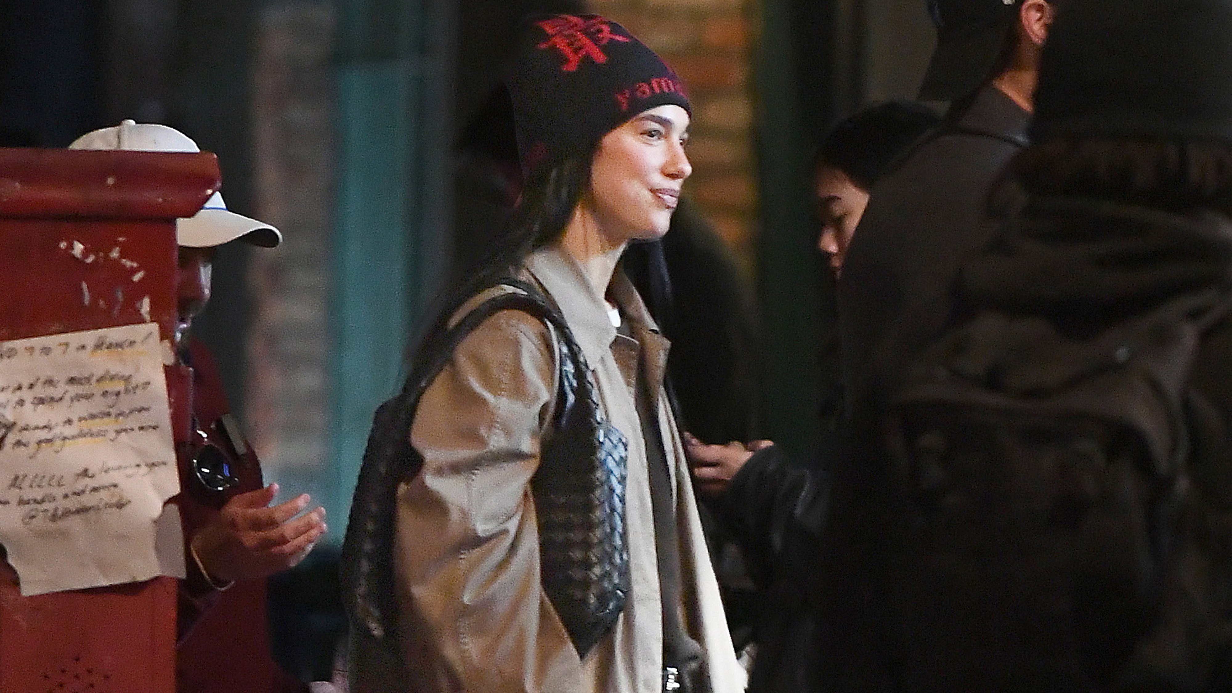 Dua lipa wears a beanie and beige coat.