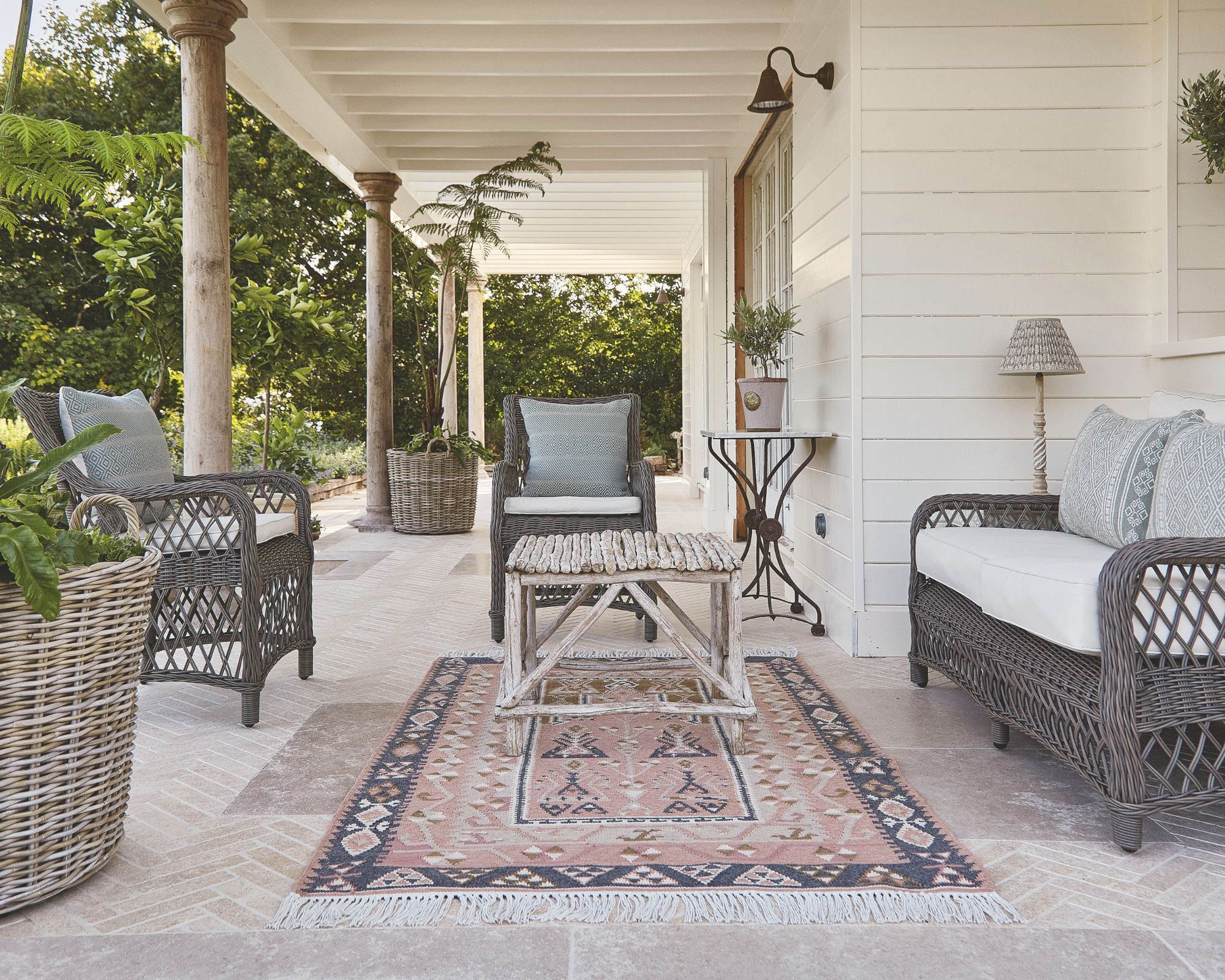 Outdoor porch with rattan furniture and a sustainable pink and grey outdoor rug