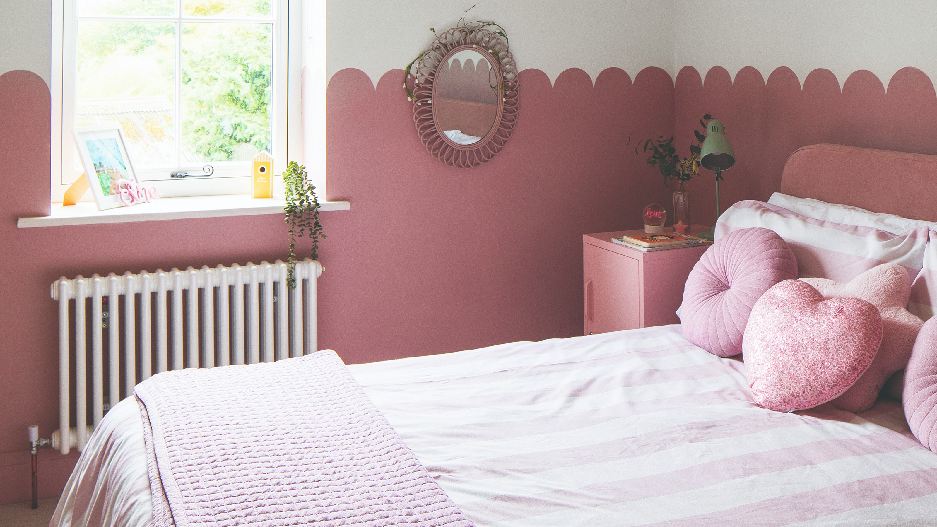 A teenage girl's bedroom with a half wall painted in pink with a scalloped edge