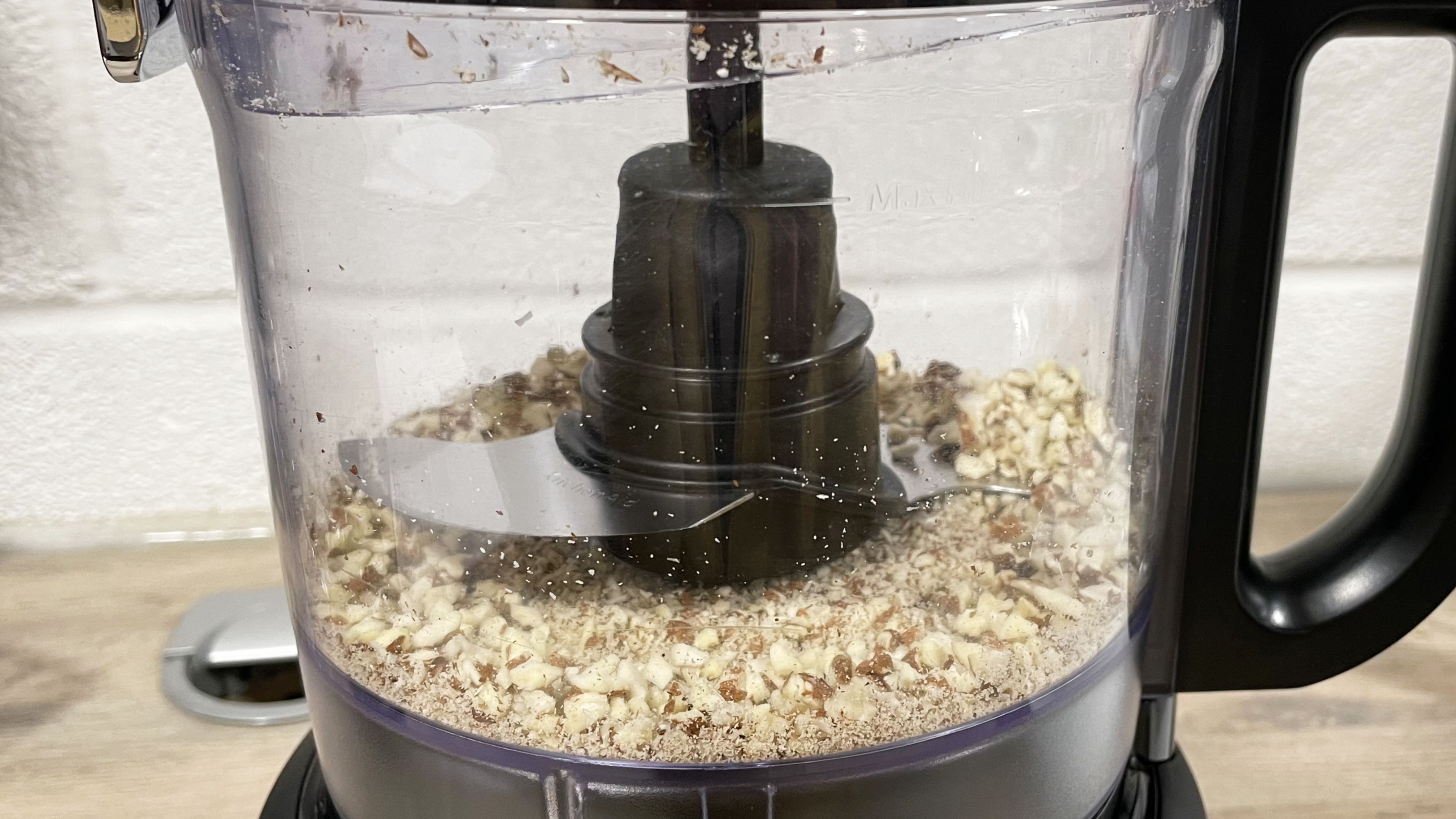 A close up of the unevenly chopped almonds in the KitchenAid 7 cup processor work bowl.