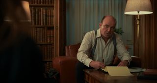 Rory Kinnear as Nicol Trowbridge, writing in a legal pad while sitting at his desk, in episode 205 of The Diplomat.