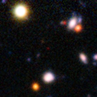 The red speck at the center of this very deep image from the European Southern Observatory's Very Large Telescope shows the galaxy NTTDF-474, one of the most distant ever to have had its distance measured accurately. This extremely faint object is one of five that have been used to chart the timeline of the re-ionization of the universe about 13 billion years ago.