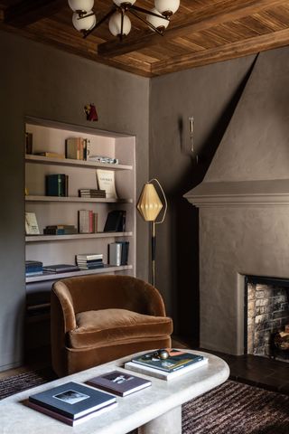Black walls and fireplace, brown velvet armchair