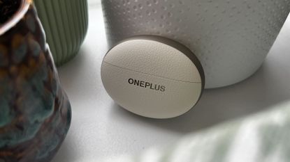 The OnePlus Buds Pro 3 on a shelf with some plants