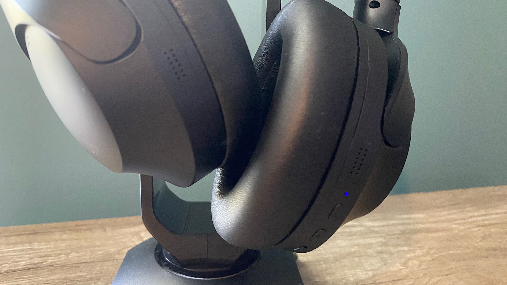 Happy Plugs Play Pro over-ear headphones on a stand, on a wooden surface