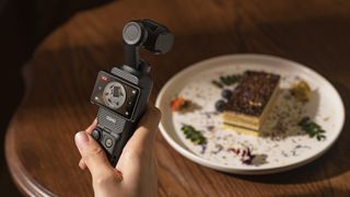 DJI Pocket 3 vlogging camera in the hand shooting video of fancy food on a table