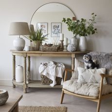 wooden console table with decorative items next to sitting chair with cushions