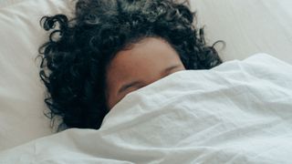 woman in bed with duvet pulled over her head