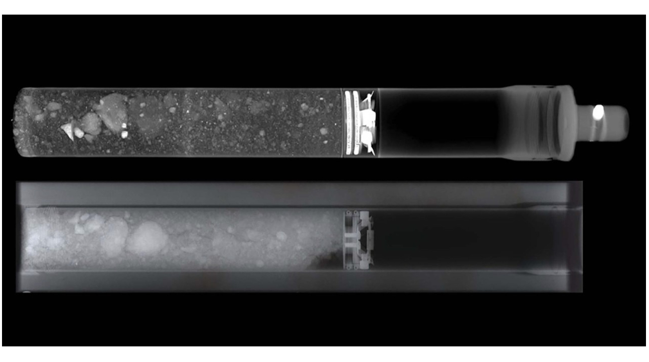 black and white photo of two long and narrow tubes that hold gray dirt and rock