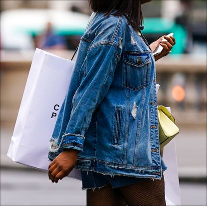 woman in denim jacket carrying shopping bags