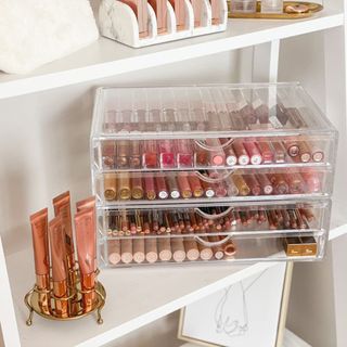Clear makeup storage box with tiered drawers and neatly arranged cosmetics