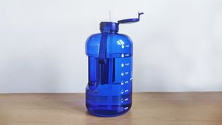 Blue Aquafit 1 gallon water bottle on wooden table