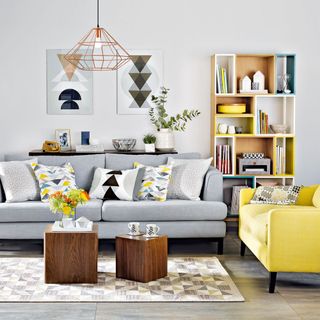 grey living room a wooden multi-color book shelf with grey and yellow furniture and wooden cube tables with copper details