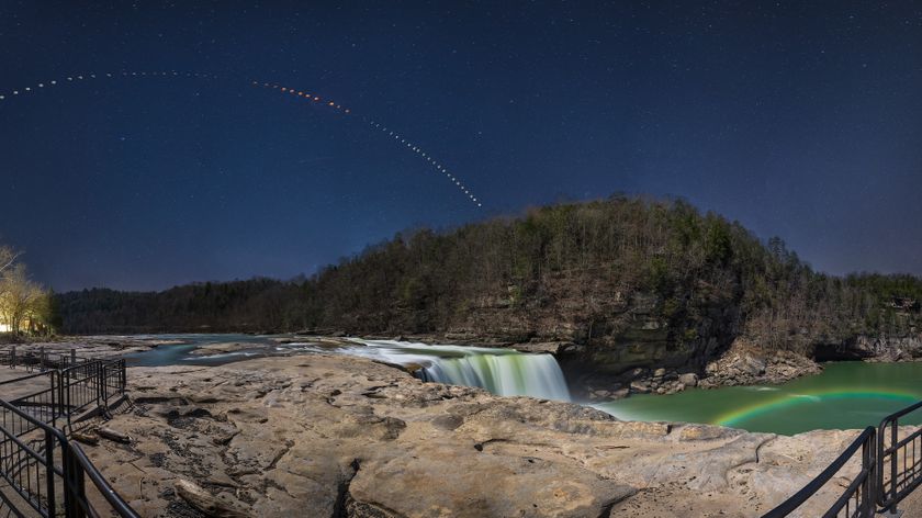 a lunar eclipse sequence arches overhead and a moonbow in the foreground in the mist of the nearby waterfall. 