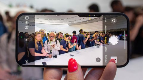 iPhone 16 smartphone held in hand in landscape showing people in camera mode in Apple Store