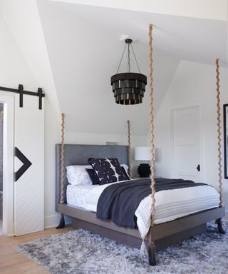 monochrome bedroom with four poster with ropes and metallic headboard fabric, black pendant and gray rug