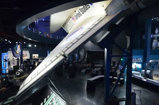 The wing of space shuttle Atlantis dips down to the bottom floor of the new Kennedy Space Center exhibition.