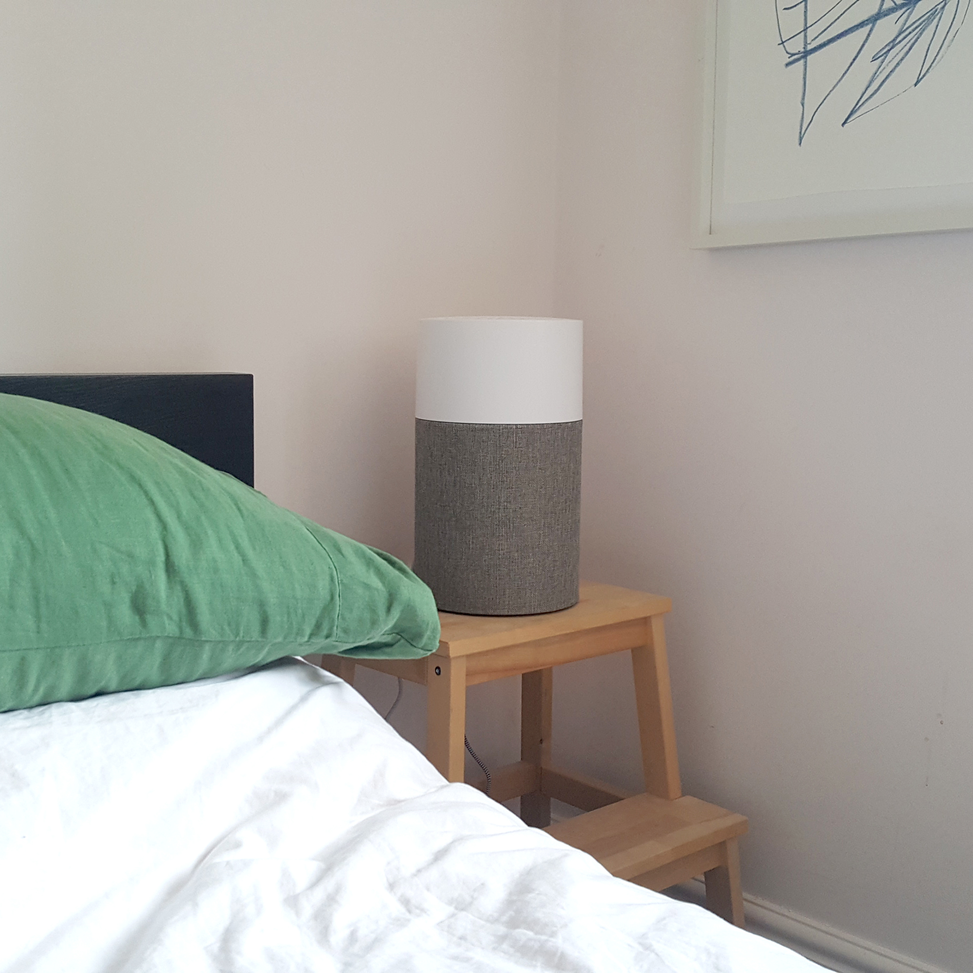 The Blueair Blue Pure 511 air purifier in a bedroom with green bedding