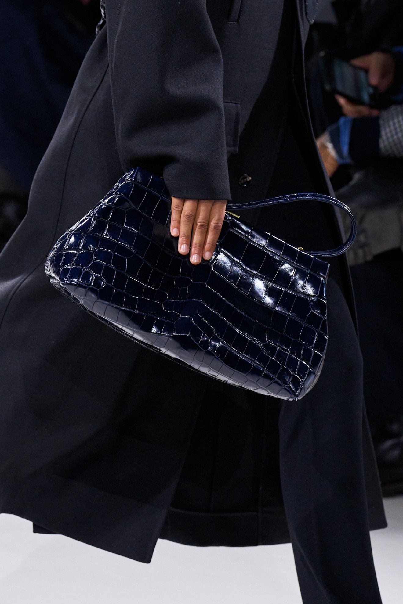 A model at the spring/summer 2026 show for Bottega Veneta wearing a navy blue croc handbag.