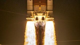 two massive side booster spew yellow orange fire lifting the core stage of a rocket as two main engines also ignite