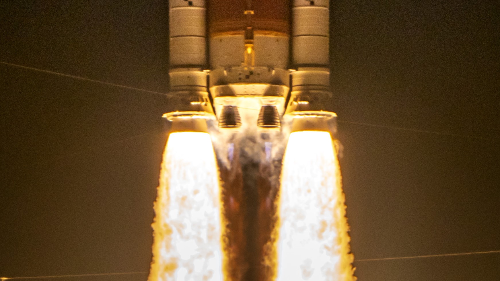 two massive side booster spew yellow orange fire lifting the core stage of a rocket as two main engines also ignite