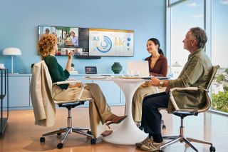 The HP | Poly new video bar being used by a smiling group of workers in a small meeting room.