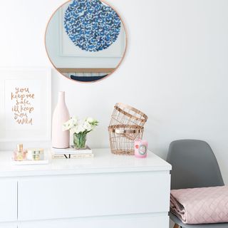 chair bedroom makeover with copper mirror and wire baskets