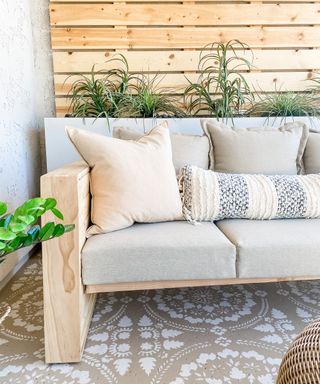 Close up of outdoor sofa on decorative patio tiled floor against wooden pallet backdrop