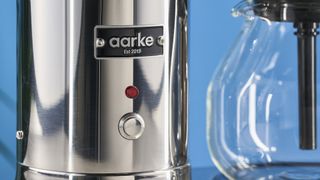 a silver drip brew coffee maker with a 10 cup capacity is photographed against a blue background