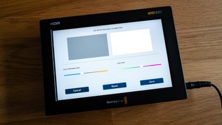 Blackmagic Video Assist 7 12G HDR video monitor displaying color settings on a wooden surface