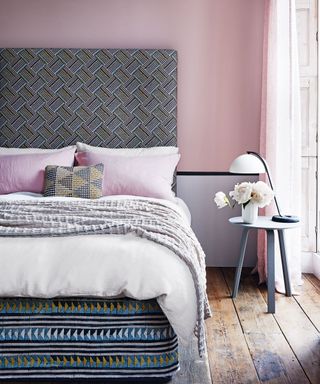 Bedroom ideas for teenagers illustrated in a pale pink room with wooden floorboards and a patterned divan bed and headboard.
