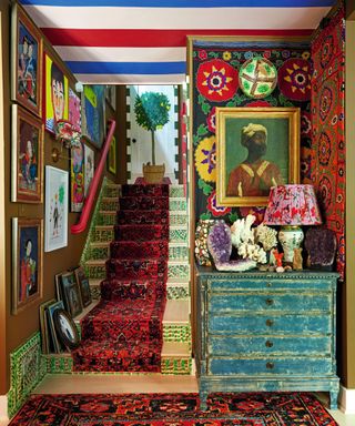 hallway with stairwell with patterned rug and stair runner and lots of artwork on walls