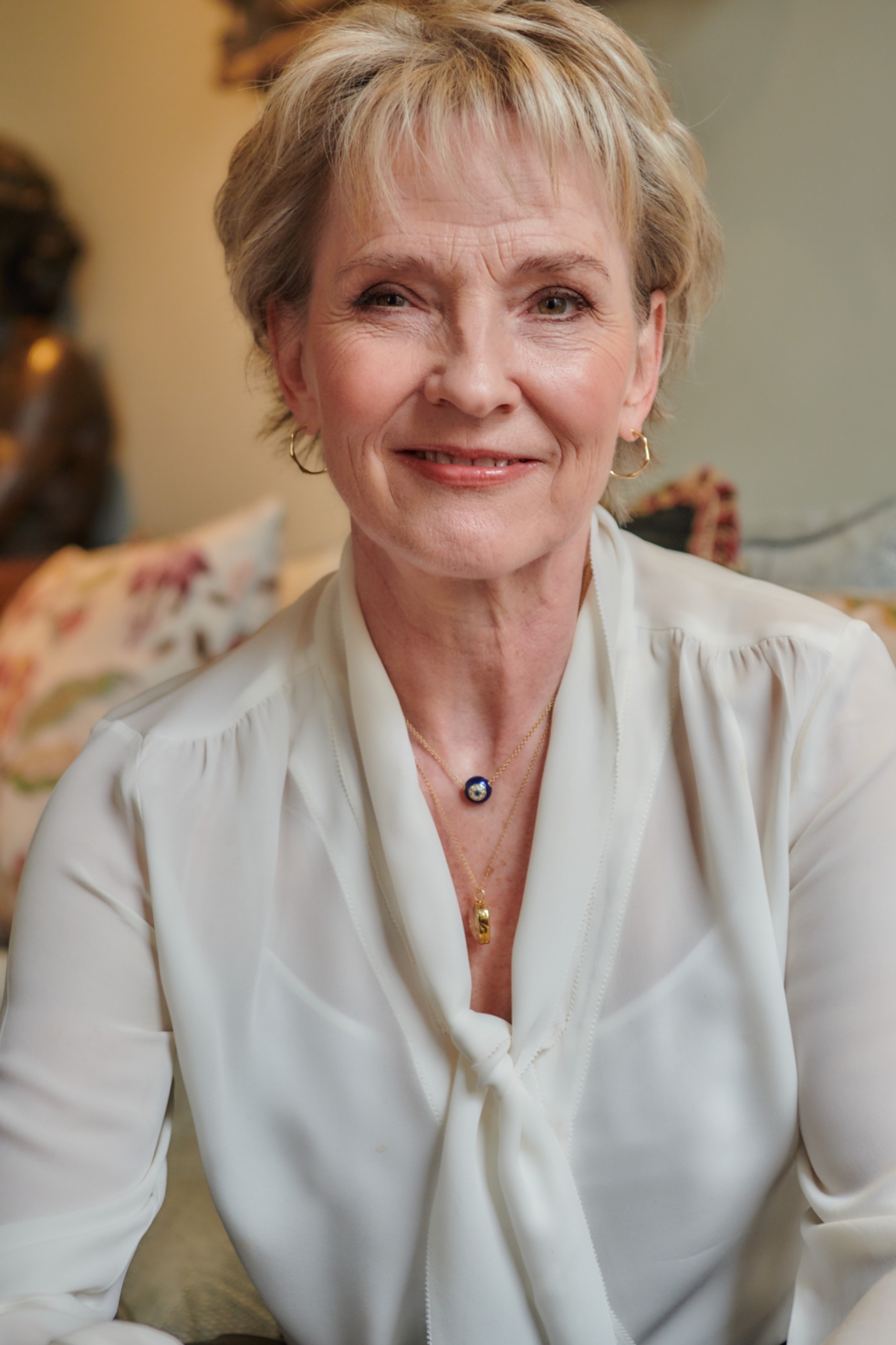 A woman wearing a white blouse smiling at the camera
