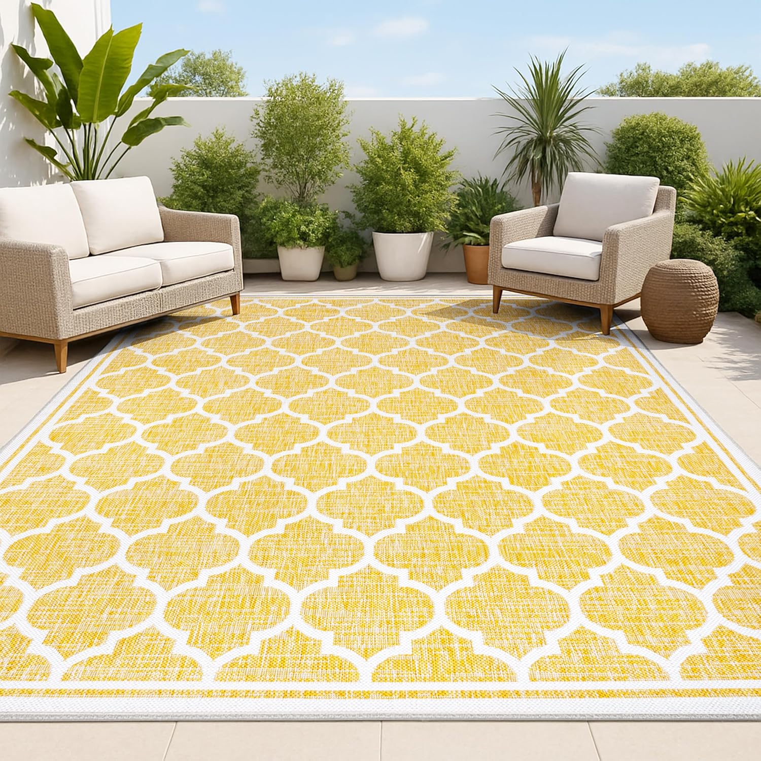 Large yellow and patterned rug in outdoor space with two armchairs, various potted trees and plants.