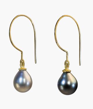 Grey pearl earrings hanging from golden hoops.