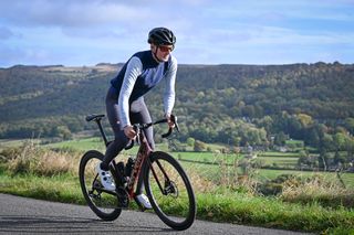 Male cyclist wearing Castelli Espresso Vest riding up a hill with view of the Peak District